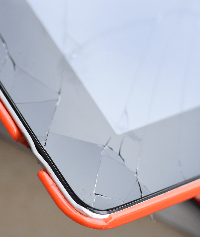 a black iPad inside an orange case, the kind typically used to protect school iPads. This iPad has a cracked screen.