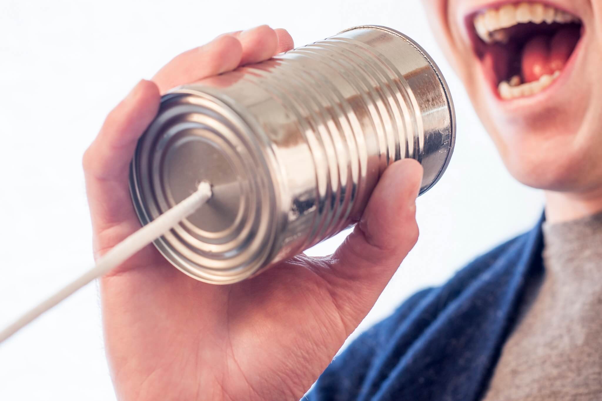 a man speaking into a tin can, which has a string coming out of the bottom.